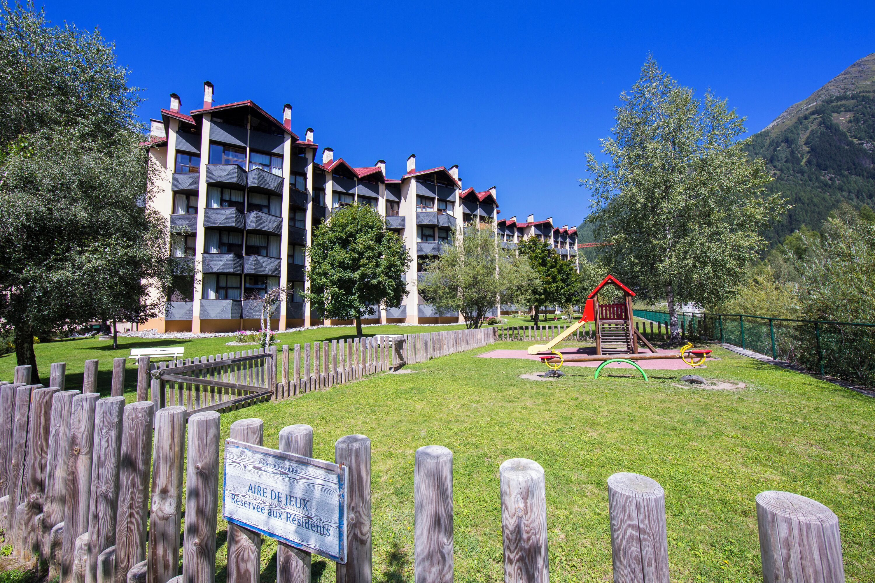 A multi-story building with balconies, a fenced playground, and a sign indicating a reserved area.