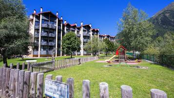 A multi-story building with balconies, a fenced playground, and a sign indicating a reserved area.