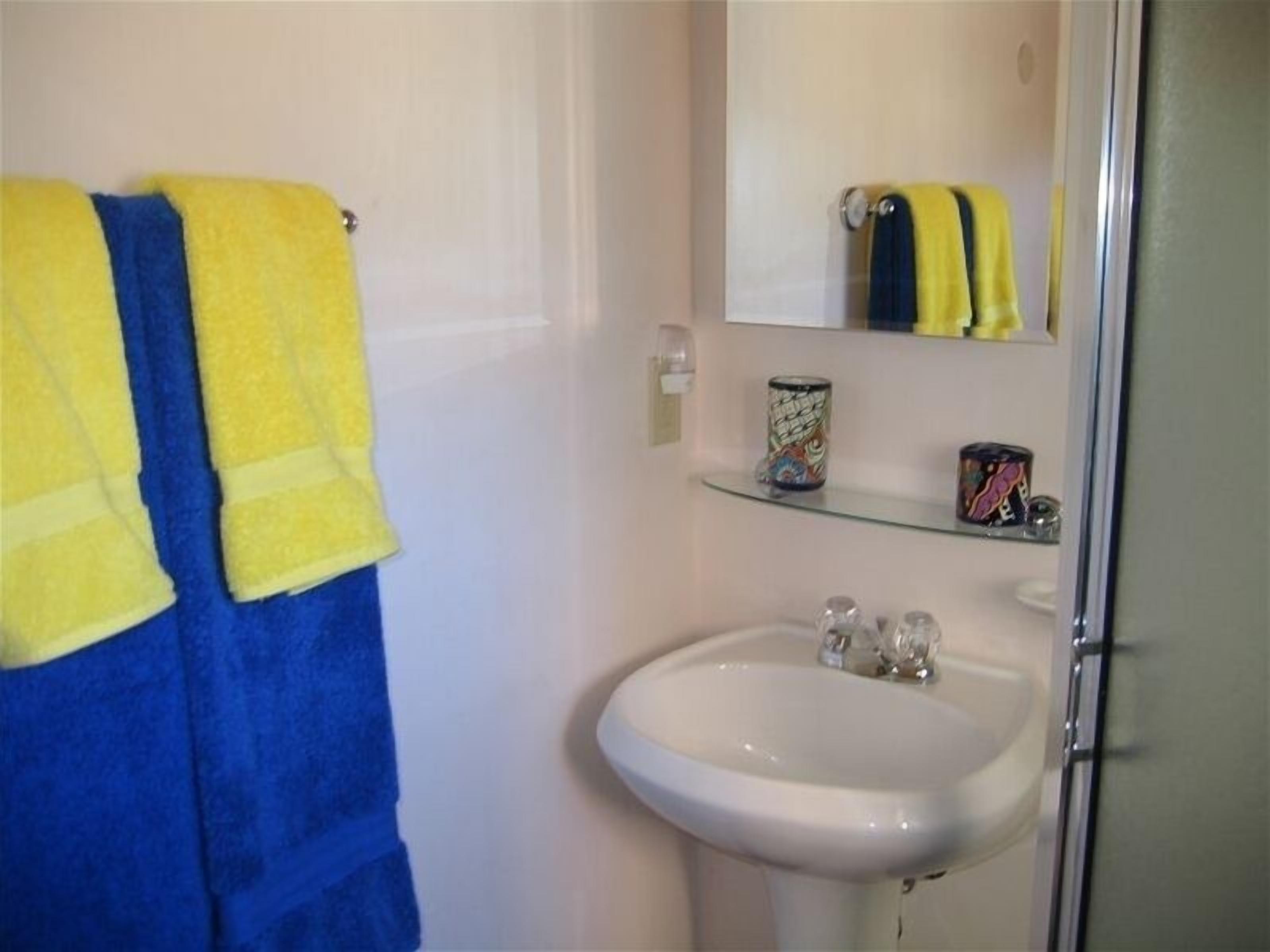 Een badkamer met een wit wastafel, een spiegel en een plankje met een blik en een doos.