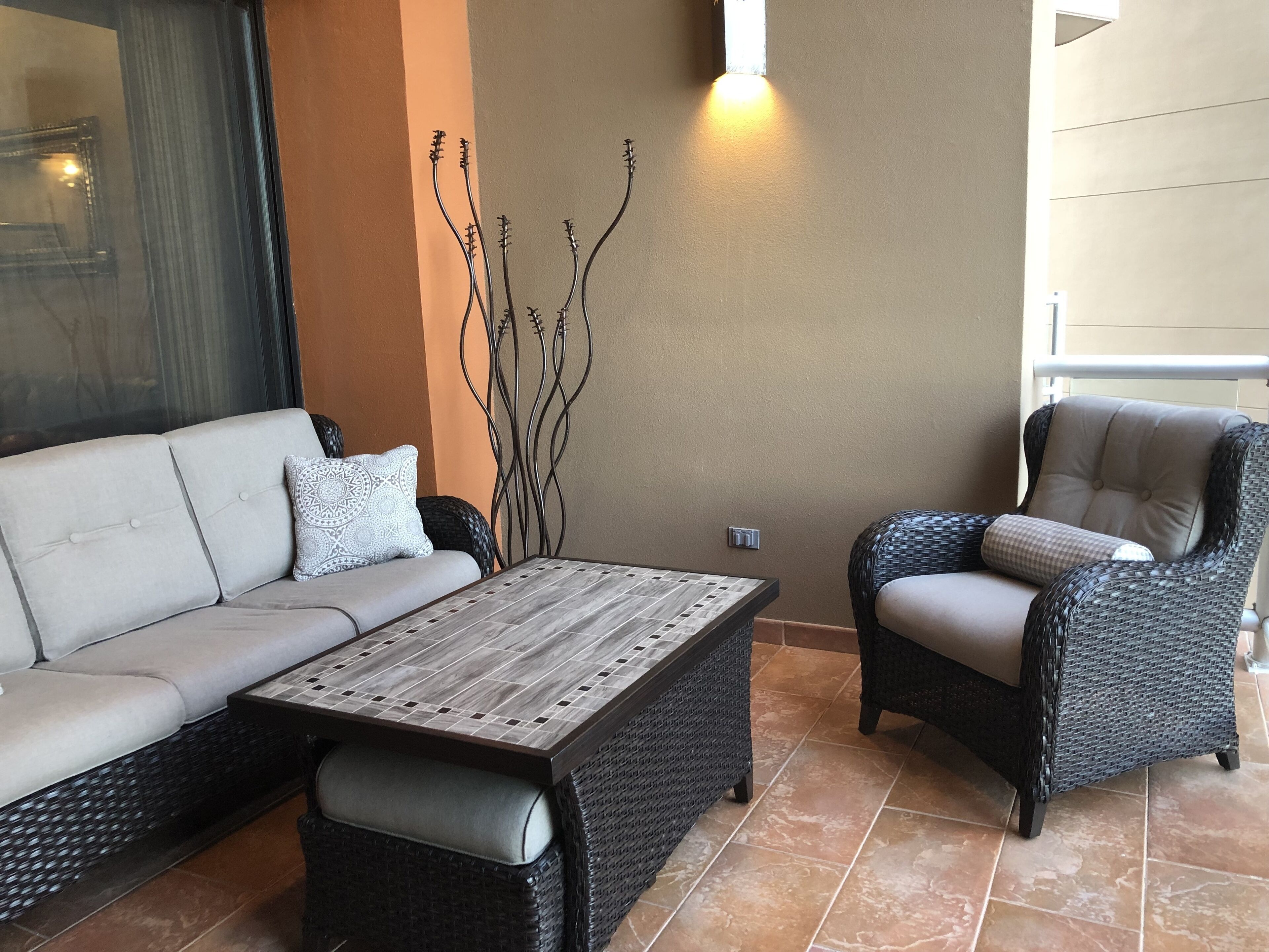 A modern outdoor seating area with a sofa, a wicker chair, and a coffee table.