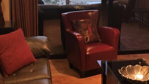 Une pièce avec un canapé en cuir, un fauteuil rouge et une vue sur l’océan.