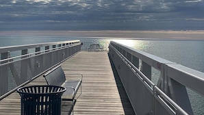A wooden pier with metal railings, benches, and a trash can. - Beautiful Beachfront Custom Log Cabin on Lake Huron (Oscoda)