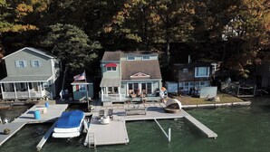 Une propriété située au bord de l’eau, dotée d’un quai, d’un bateau et d’une maison avec une véranda.