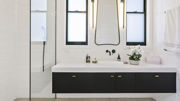 A modern bathroom with a white vanity, black cabinets, and a large mirror above the sink. - Currawong Song Noosa Heads (Noosa Heads)
