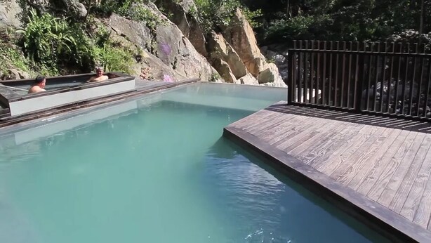 Une piscine dotée d’une terrasse en bois et d’une clôture en métal.