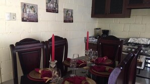 Une table à manger dressée pour quatre personnes, avec des serviettes rouges, des verres à vin et une bougie.