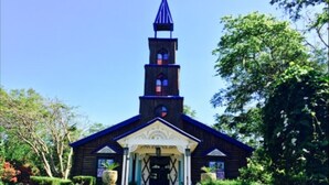 Une église en bois dotée d’un clocher et d’une entrée blanche.