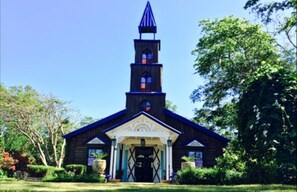 Stunning church with a prominent steeple and symmetrical facade, set amidst lush greenery and trees.
