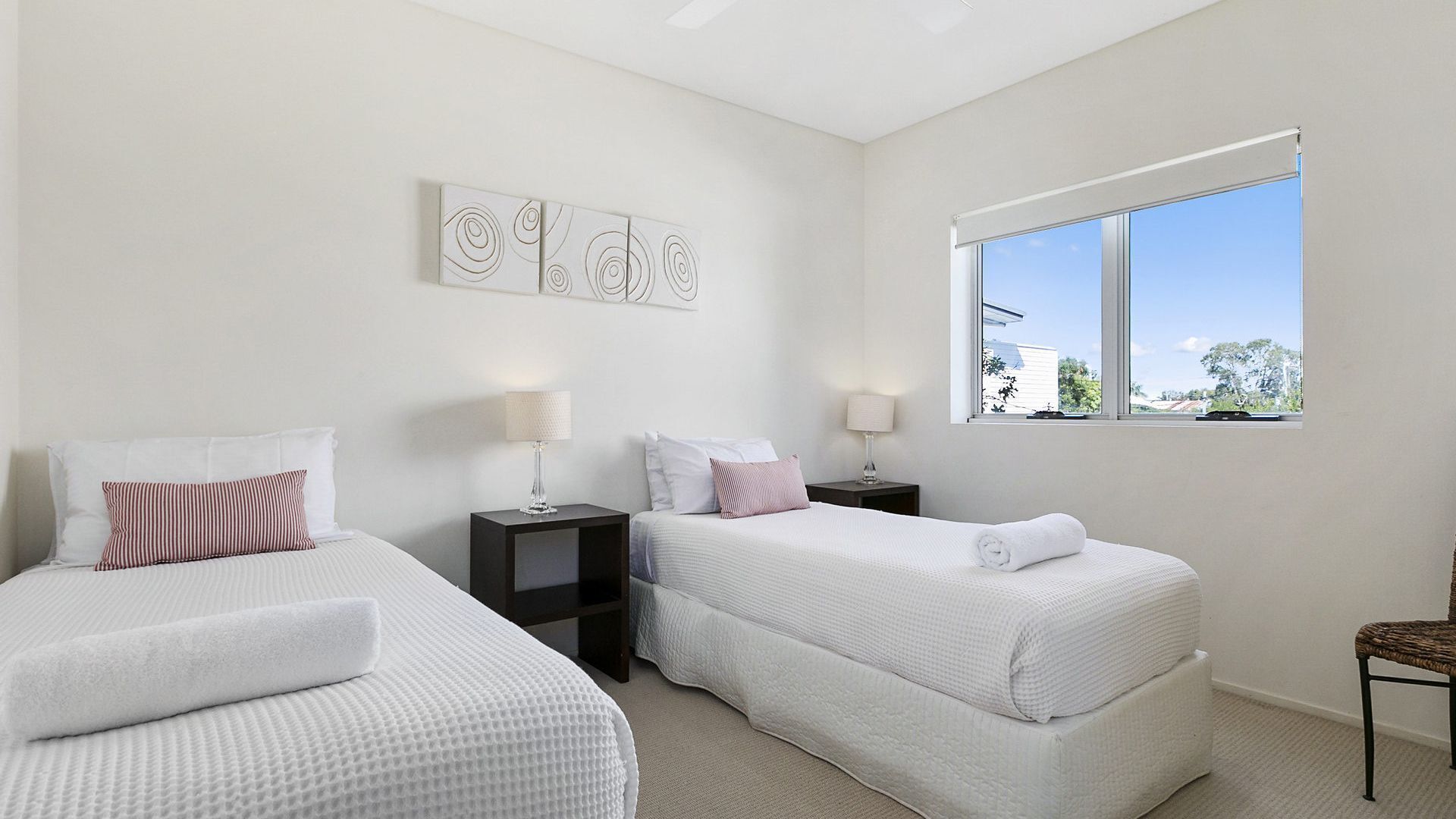 Una habitación de hotel con dos camas, un ventanal con vistas y una pared decorada con arte abstracto.