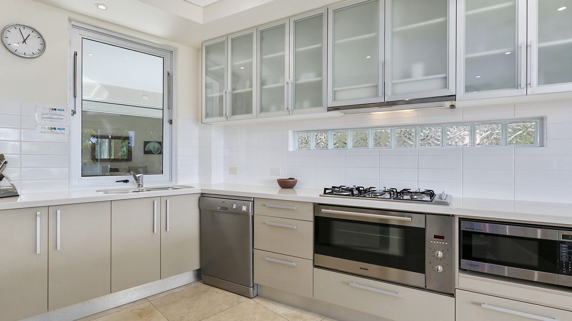 A modern kitchen with white cabinetry, a dishwasher, an oven, a microwave, and a gas stove.