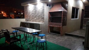 An outdoor patio with a brick oven, a table, and chairs.