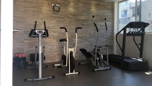 A gym with various exercise equipment including an elliptical, a stationary bike, and a treadmill.