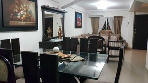 A dining area with a glass table, black chairs, and a painting on the wall.