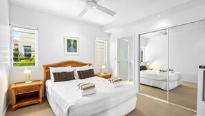 A modern bedroom with a large bed, a ceiling fan, and a large mirror. - No. One Park 4 Sunshine Beach (Sunshine Beach)