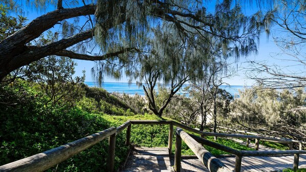 Eine Holztreppe führt zu einem Strand mit Blick auf das Meer.