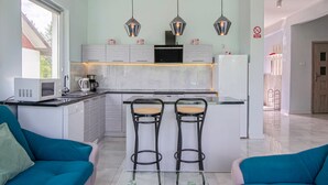 Une cuisine moderne dotée d’un îlot central, de deux tabourets de bar et d’une table à manger avec des chaises.