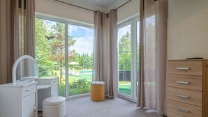 Une salle de bain moderne avec un meuble-lavabo, des toilettes et une grande fenêtre donnant sur une piscine et un espace verdoyant.