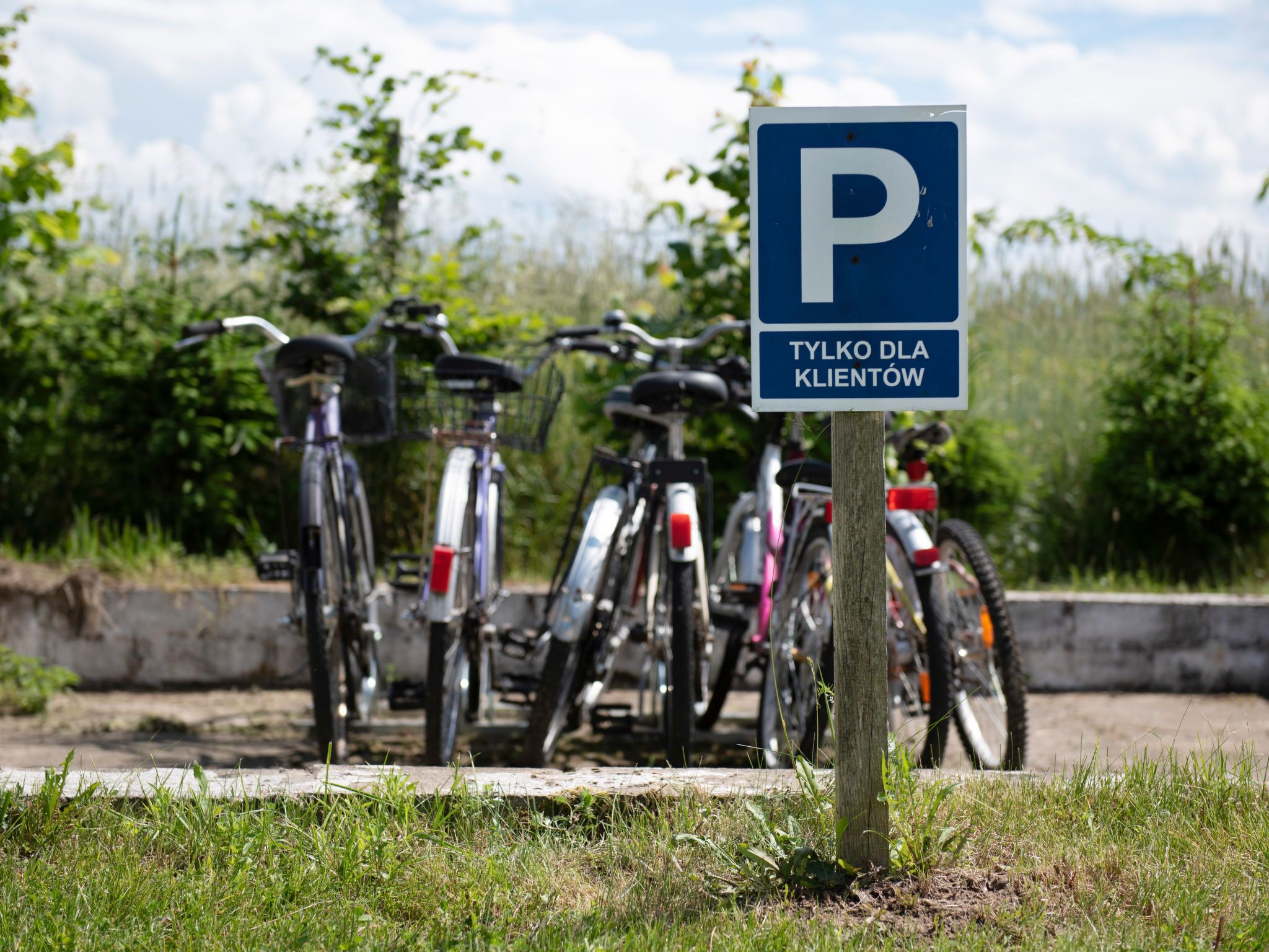 A parking sign with bicycles parked in the background.