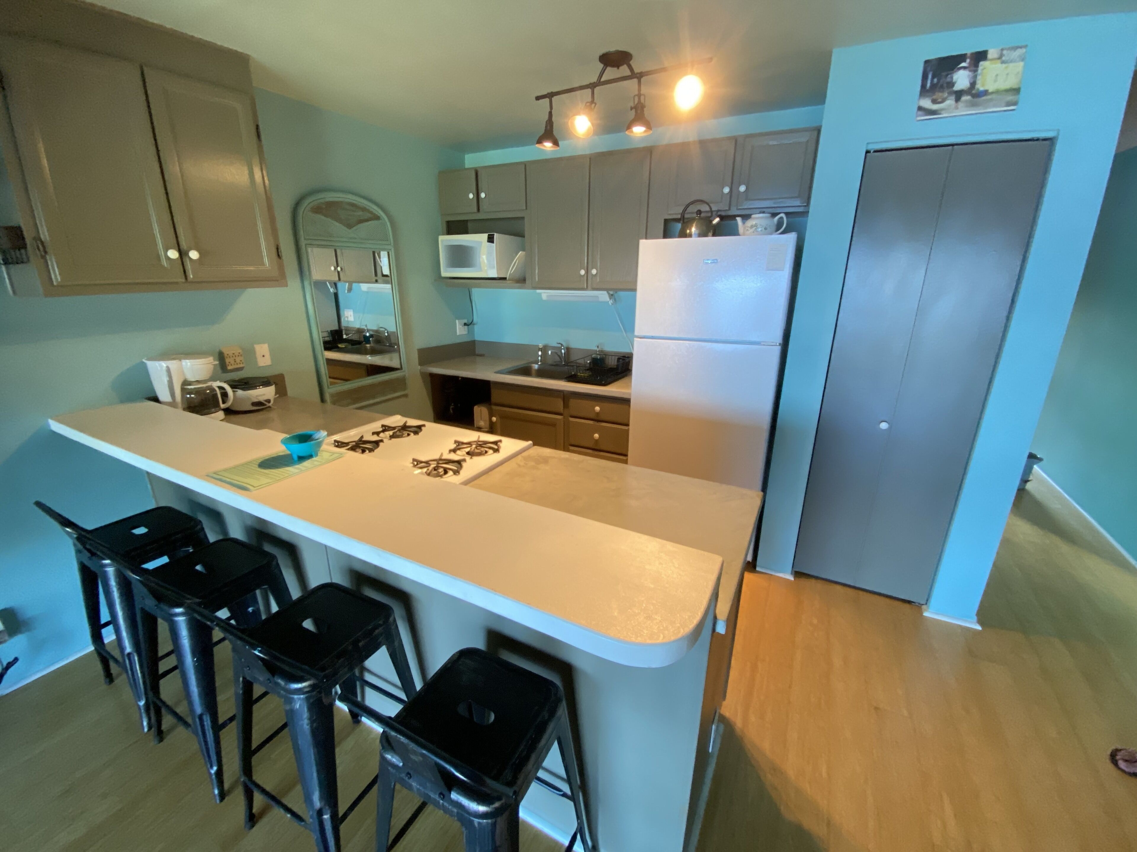 Een moderne keuken met een centraal eiland, barstoelen, een magnetron, een koelkast en een spoelbak.