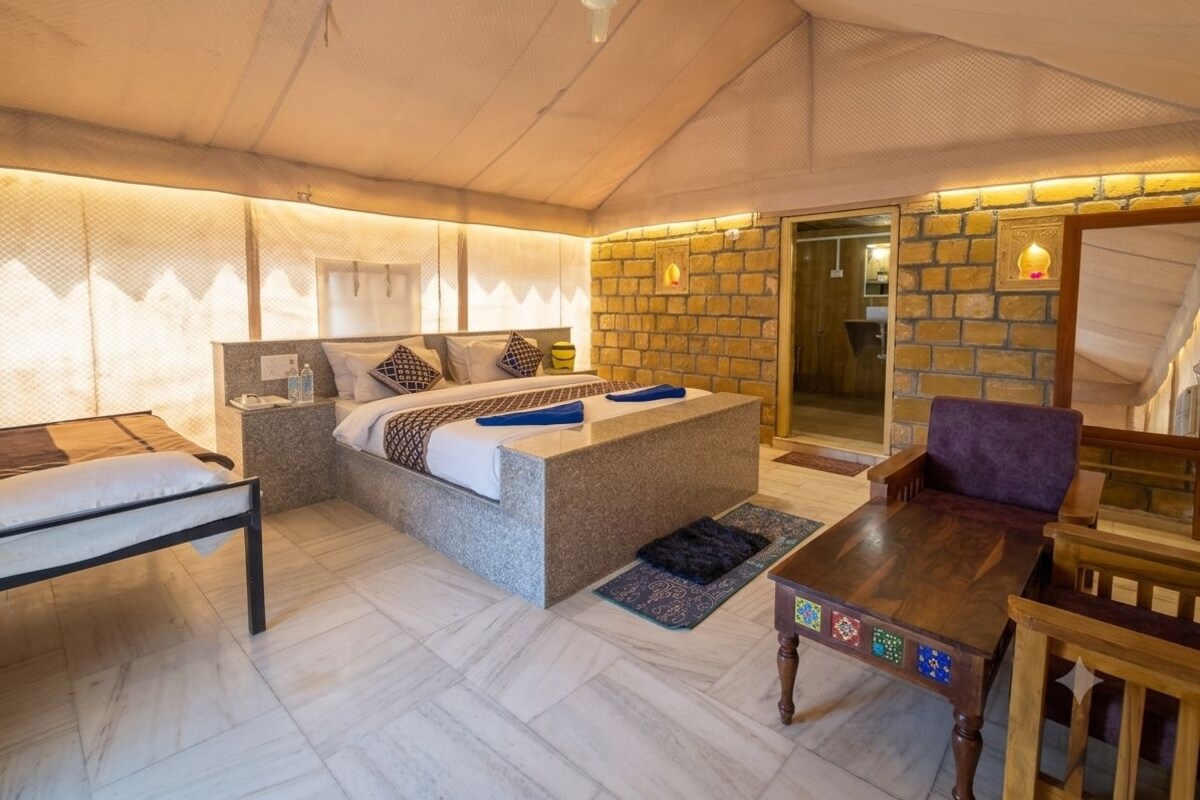 Une chambre à coucher comprenant un lit, une table de chevet et une petite table en bois dont le plateau est décoré d’un motif.