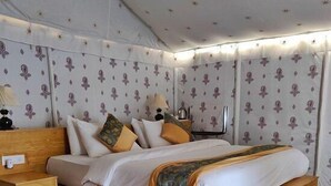 Una habitación con cama de madera, papel tapiz estampado y una alfombra colorida.