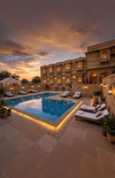 A pool area with lounge chairs and a building with traditional architecture.