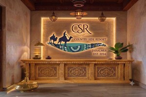 A reception desk with a carved wooden design, a sign reading 'CSR Country Side Resort Jaisalmer EST. 2014', and a decorative lamp.