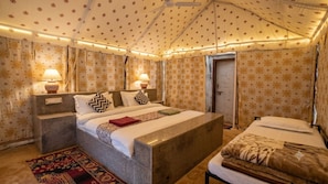 A bedroom with a large bed, bedside lamps, patterned curtains, and a decorative ceiling.