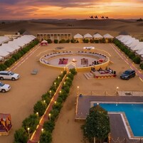 A desert resort with tents, a central courtyard, a swimming pool, and camels in the background.