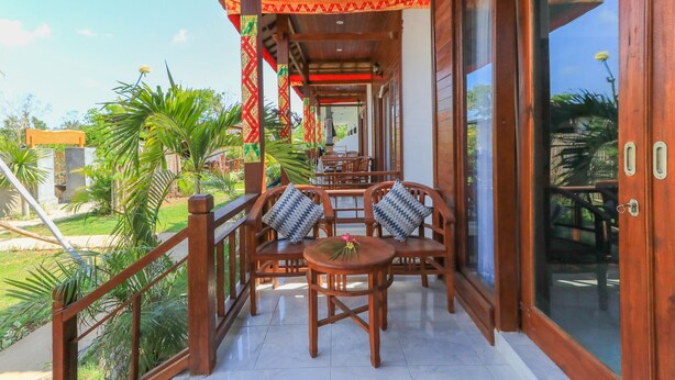 Un balcon en bois donnant sur le jardin, aménagé avec des chaises et une table en bois.