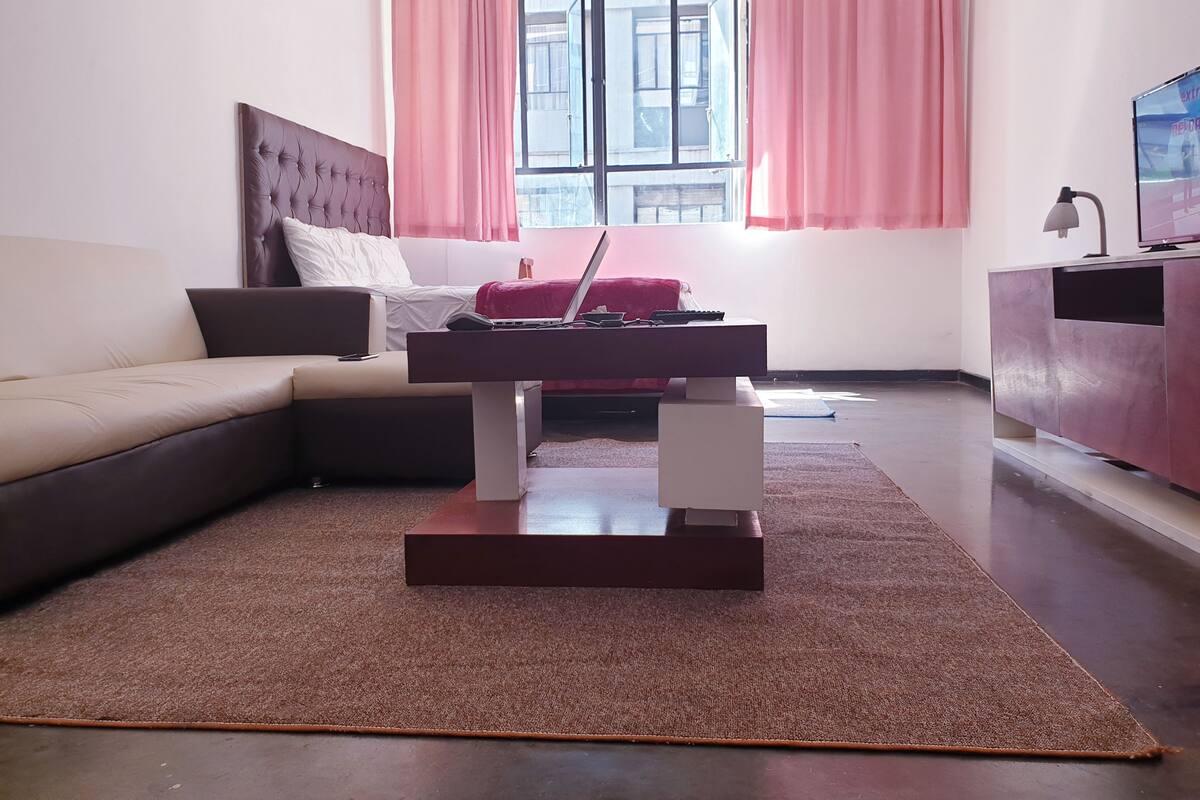 Ein modernes Wohnzimmer mit einem Ecksofa, einem Couchtisch und einem Fernseher auf einem Schrank.