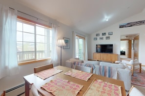 Relax in this open-plan living space with a large window offering a view of the outdoors, a flat-screen TV, and comfortable seating.
