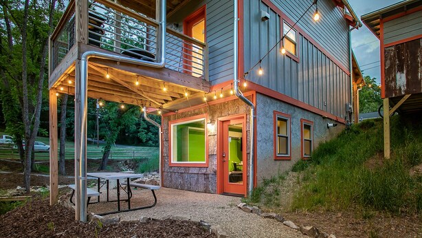 A two-story house with a covered patio, outdoor seating, and string lights. - Bike Studio Apartment Near Everything! (Brevard)