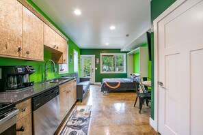 Compact apartment with a kitchenette, sofa, and bed, offering a view of the outdoors.