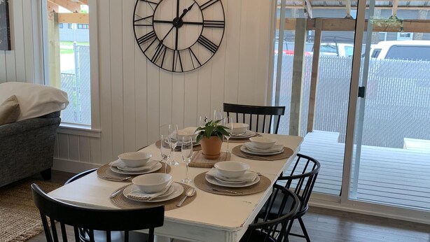 A dining area with a large table set for four, surrounded by black chairs, a chandelier, and a large wall clock. - Updated charming home - perfectly located between Downtown & Kidsport Complex (Kalispell)