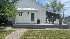 A white single-story house with a covered porch and outdoor seating. - Updated charming home - perfectly located between Downtown & Kidsport Complex (Kalispell)