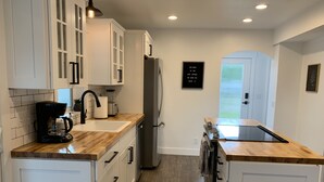 A modern kitchen with white cabinets, a coffee maker, a sink, and a refrigerator. - Updated charming home - perfectly located between Downtown & Kidsport Complex (Kalispell)