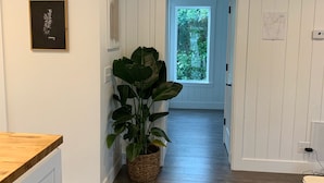 A hallway with wooden flooring, a potted plant, and a window leading to a bright room. - Updated charming home - perfectly located between Downtown & Kidsport Complex (Kalispell)