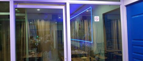A restaurant interior with tables and chairs, a blue neon light, and a no smoking sign.