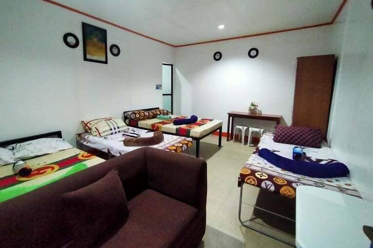 A room with two beds, a sofa, a small table, and a chair.