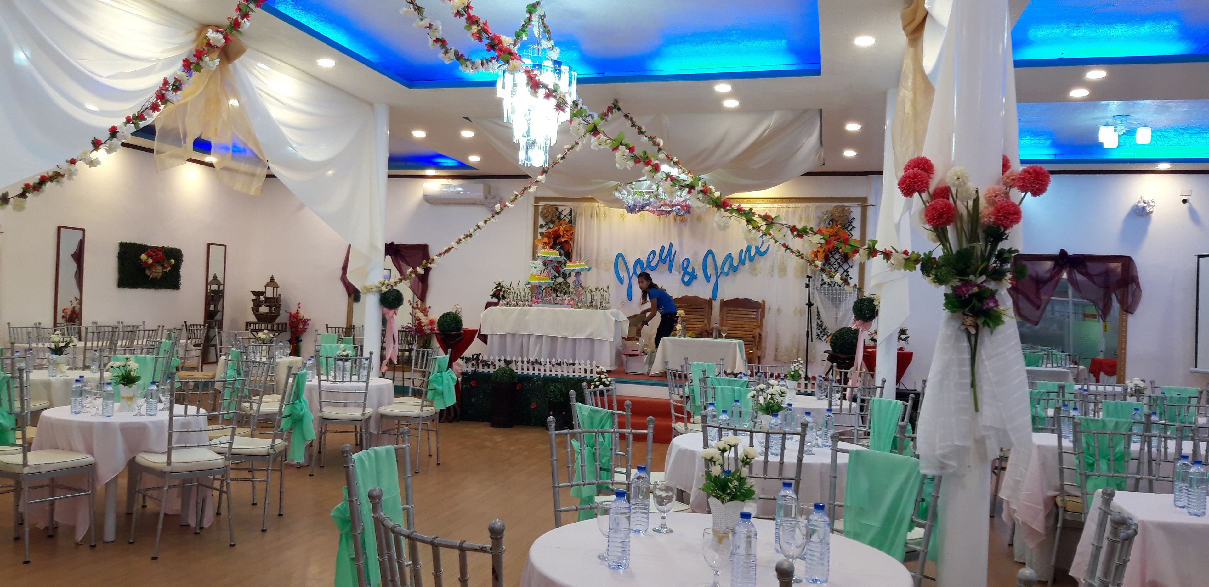 A banquet hall with round tables, chairs, and floral decorations.