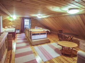 Kodikas ullakkohuone, jossa on sänky, työpöytä, tuoli ja pieni pöytä.