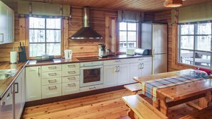 Cocina estilo cabaña con paredes de madera, una isla central y un ventanal amplio.