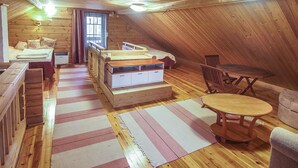 Un dormitorio acogedor en el ático con techo de madera, cama, escritorio, silla y una pequeña mesa.