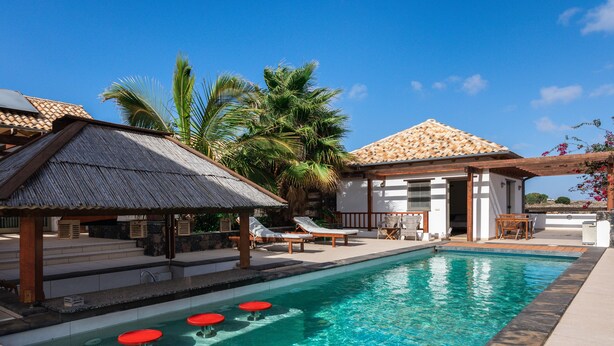 A swimming pool with lounge chairs and a bar area.