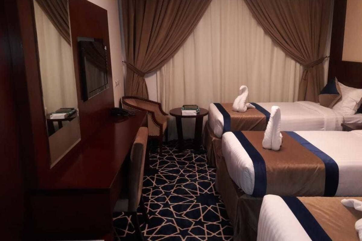 Une chambre d’hôtel avec deux lits, un bureau, une chaise, une petite table et un miroir.