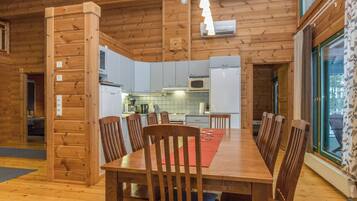 A wooden interior with a dining table, chairs, and a kitchen area.