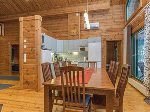 A wooden interior with a dining table, chairs, and a kitchen area. - Villa tilia by Interhome (Pertunmaa)