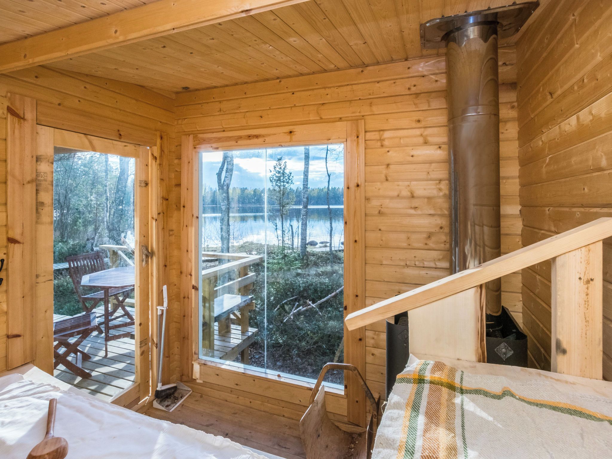 A wooden cabin interior with a large window overlooking a lake and forest.