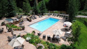 A pool area with a stone bridge, lounge chairs, and a well-maintained garden. - Ski In and Out Condo in Lionshead Village w/ Pool, Hot Tubs, and Lovely Views (Vail)